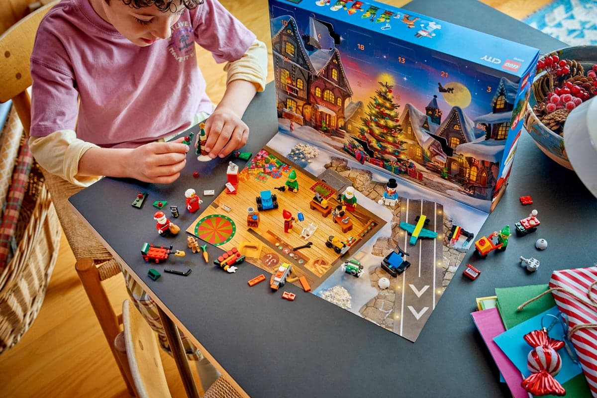 Et barn bygger LEGO City-figurer på spillematten fra kalenderen, med esken stående bak